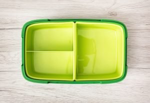Green plastic box for food storage on the wooden background